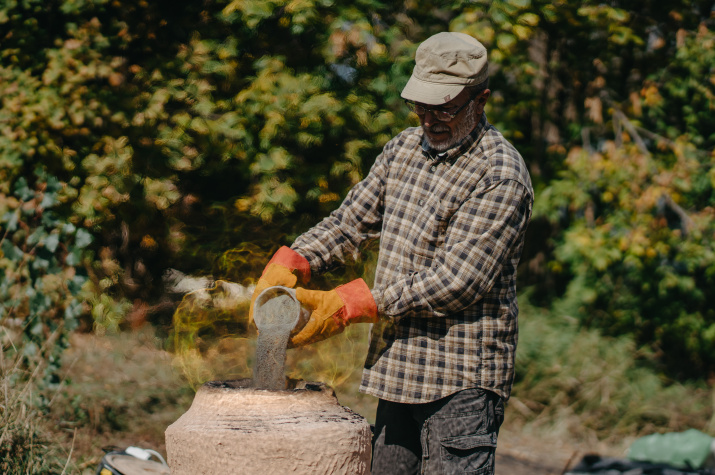 Сергей Богданов помещает шихту в медеплавильную печь. Фото Анна Майко
