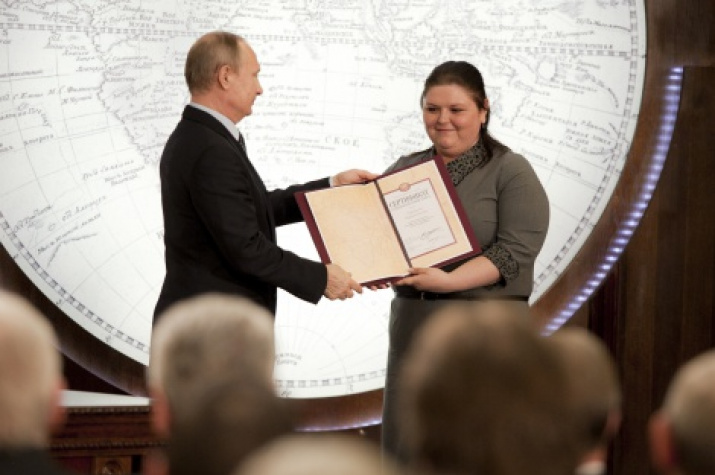 The Chairman of the Board of Trustees of the Russian Geographical Society, The President of Russia, Vladimir Putin is handing in the grant of the Russian Geographical Society to the participant of the Summer School Tatyana Oberukhtina