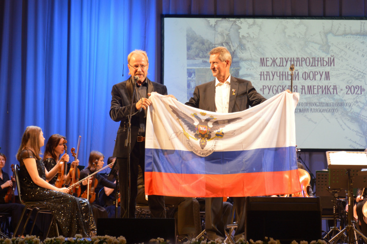 Президент Московского историко-просветительского общества «Русская Америка». Владимир Колычев вручает Михаилу Малахову флаг Российско-американской компании. Фото Виктора Шляхина Президент Московского историко-просветительского общества «Русская Америка». Владимир Колычев вручает Михаилу Малахову флаг Российско-американской компании